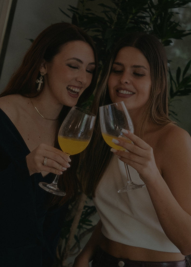 Duas mulheres a brindar com sangria de maracujá.