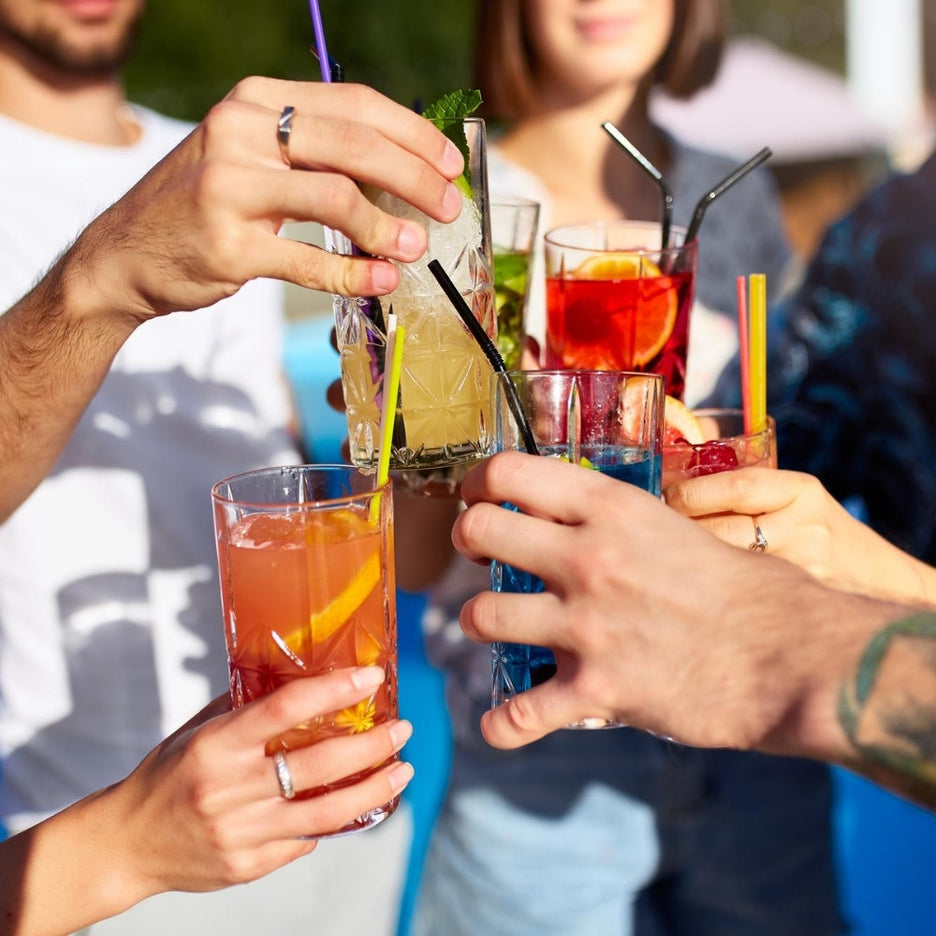 Grupo de amigos a brindar com cocktails coloridos ao ar livre