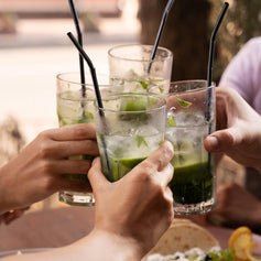 Grupo de amigos a brindar com bebidas de lima e hortelã ao ar livre