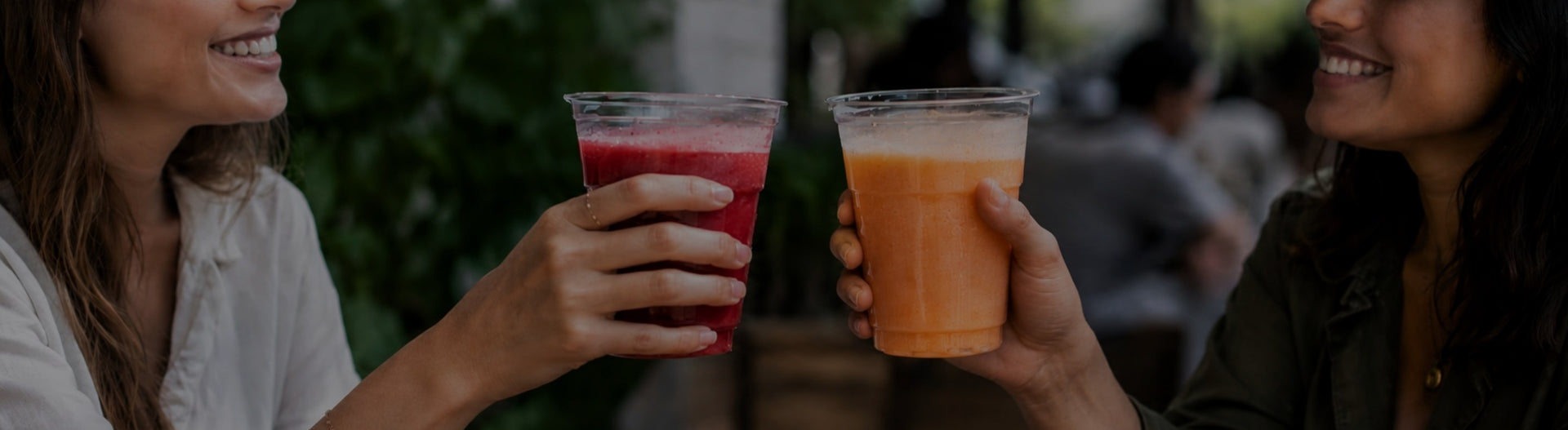 Duas mulheres a brindar com bebidas de morango e pêssego, preparadas com purés de fruta da DOuMIX?